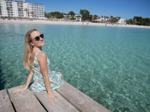 Victoria sitting on a pier next to turquoise blue water in Mallorca
