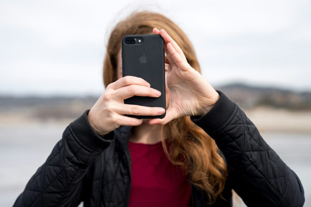 Woman with red hair taking a photo on her iphone