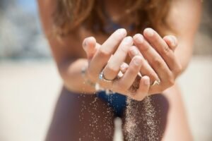 Close up of woman holding sand in her hands at the beach