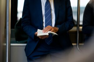 Businessman in blue suit holding a book on public transportation
