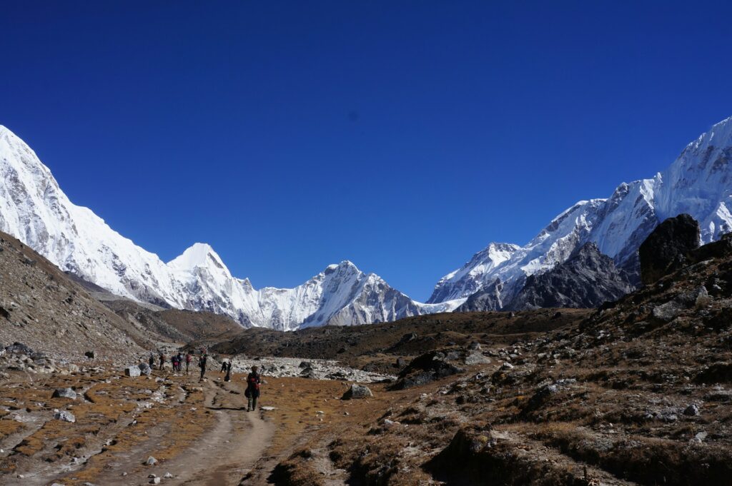 People trekking through the mountains at Everest Base Camp on a blue day