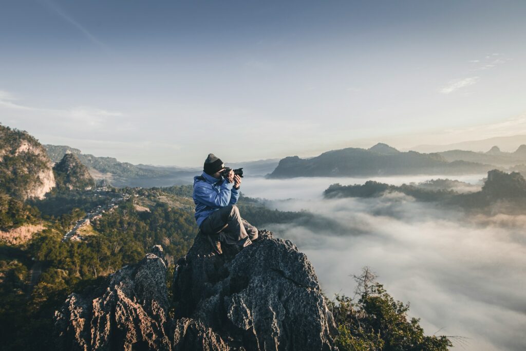 Photographer on a cliff holding a professional camera taking a picture of the view