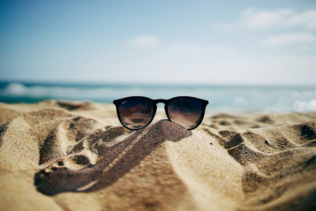Sunglasses on the sand next to the ocean
